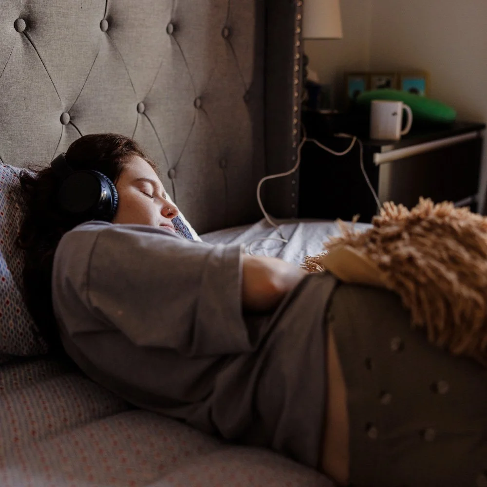 Persona durmiendo con auriculares en la cama, en un ambiente tranquilo y relajado.